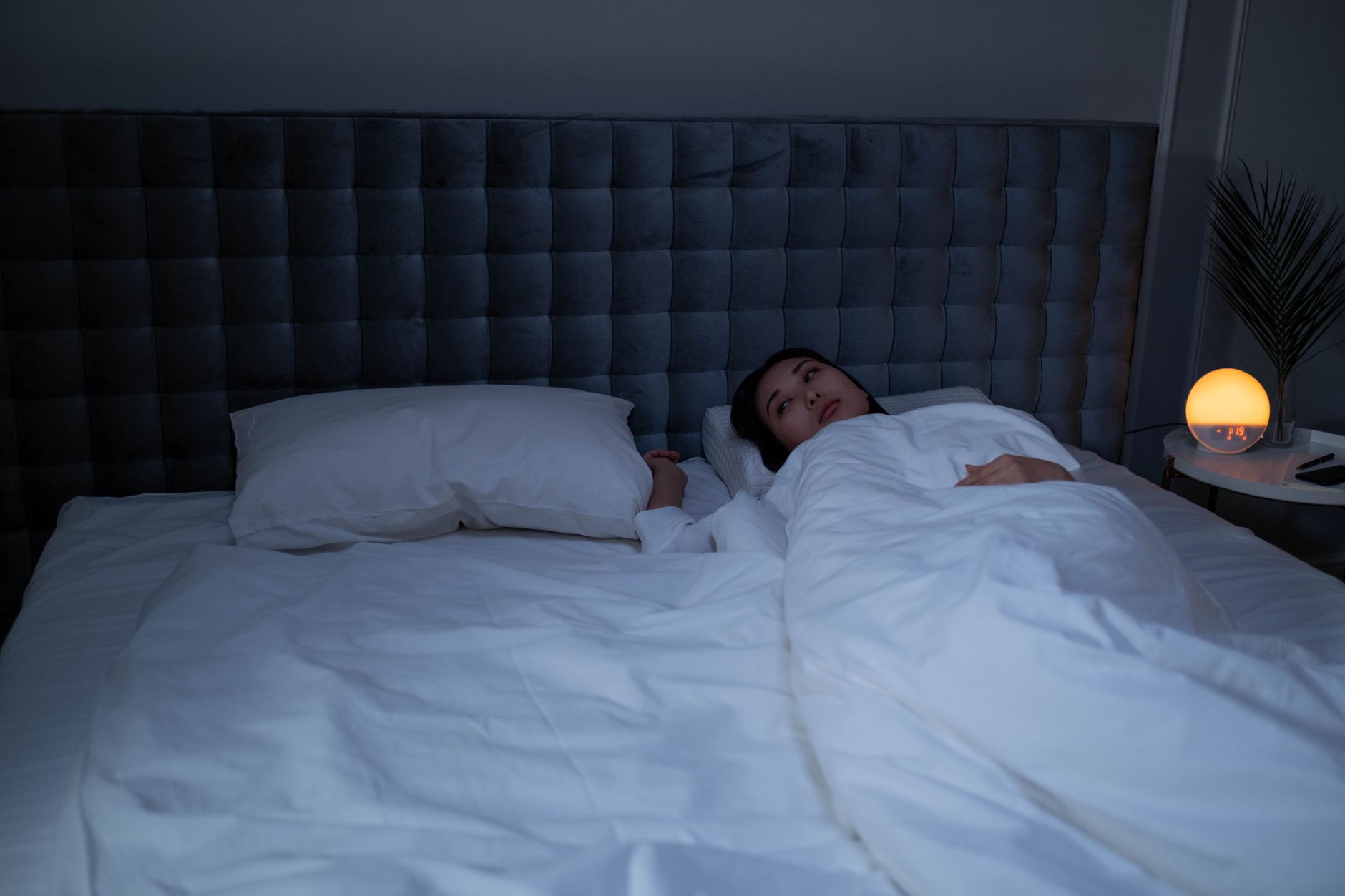 夜のベッドで眠れずに考え込む女性