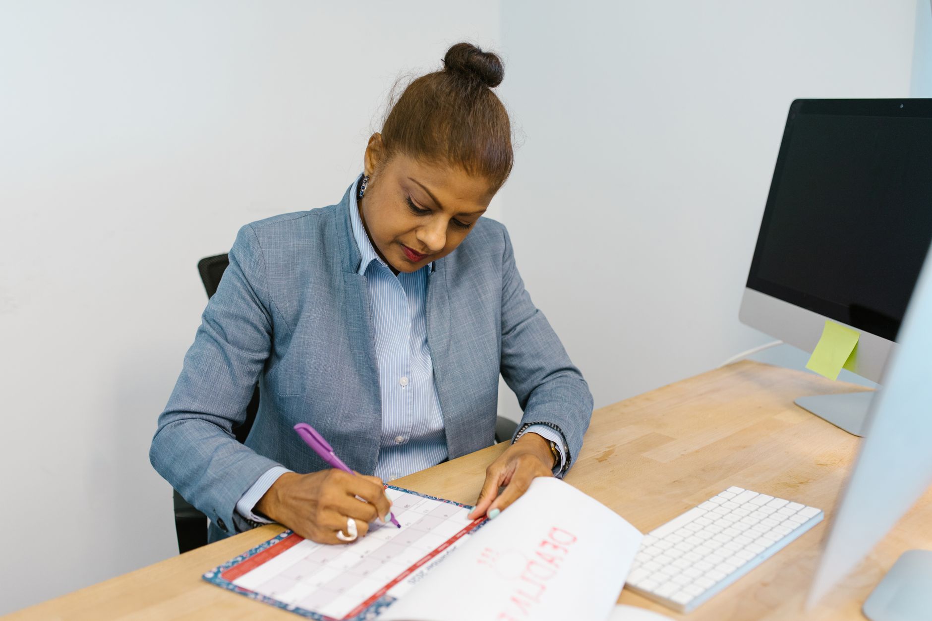 デスクでカレンダーに予定を書き込む女性