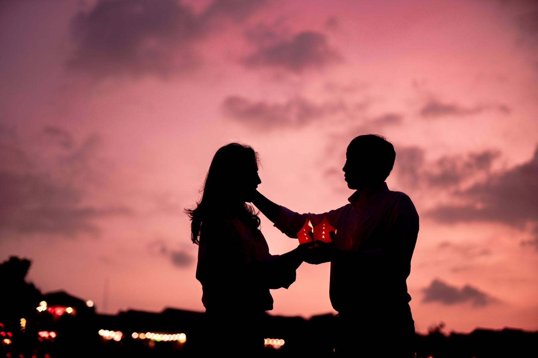 夕焼け空を背にランタンを挟んで向き合う二人のシルエット
