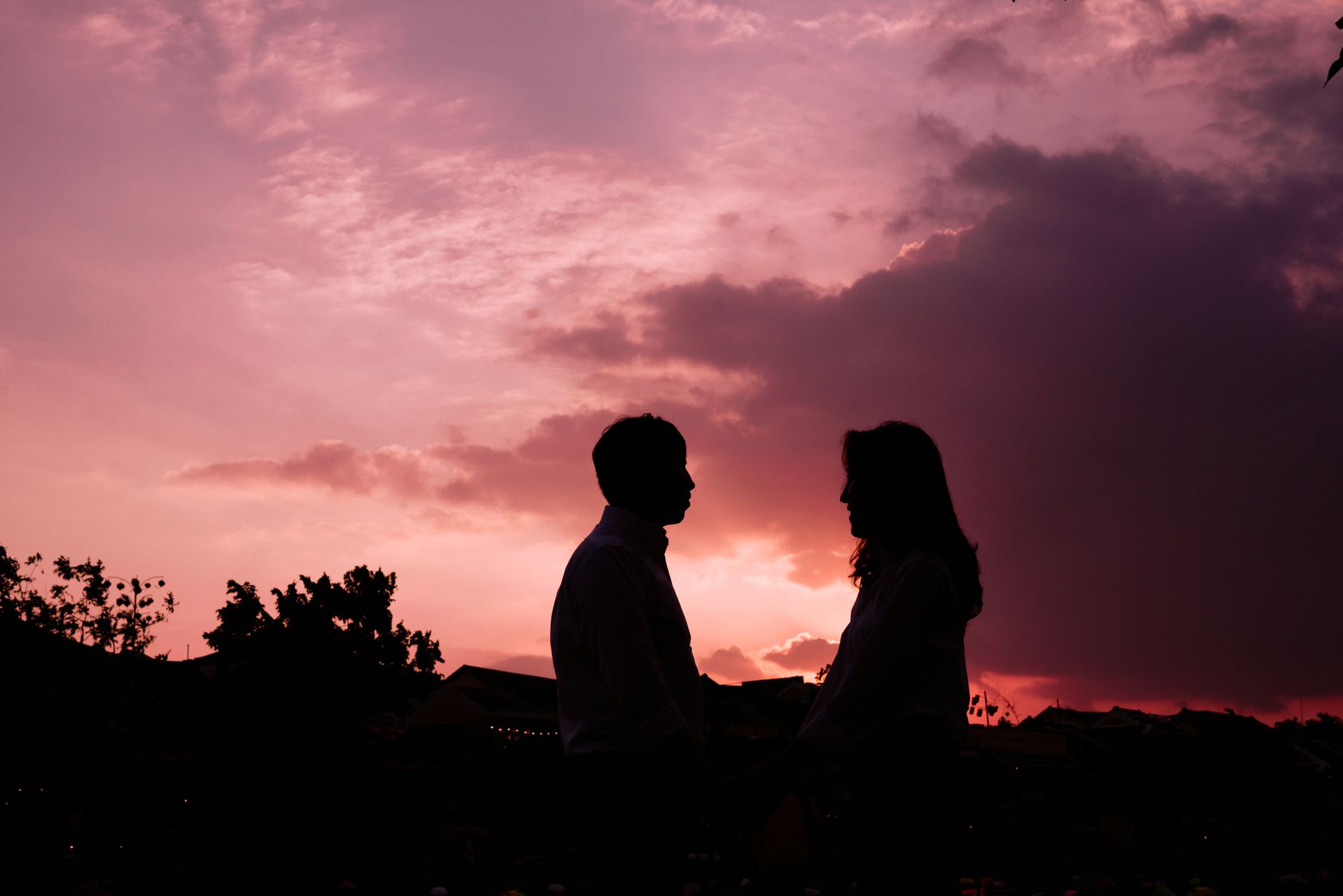 紫色の夕焼け空の下で向かい合って立つ二人のシルエット