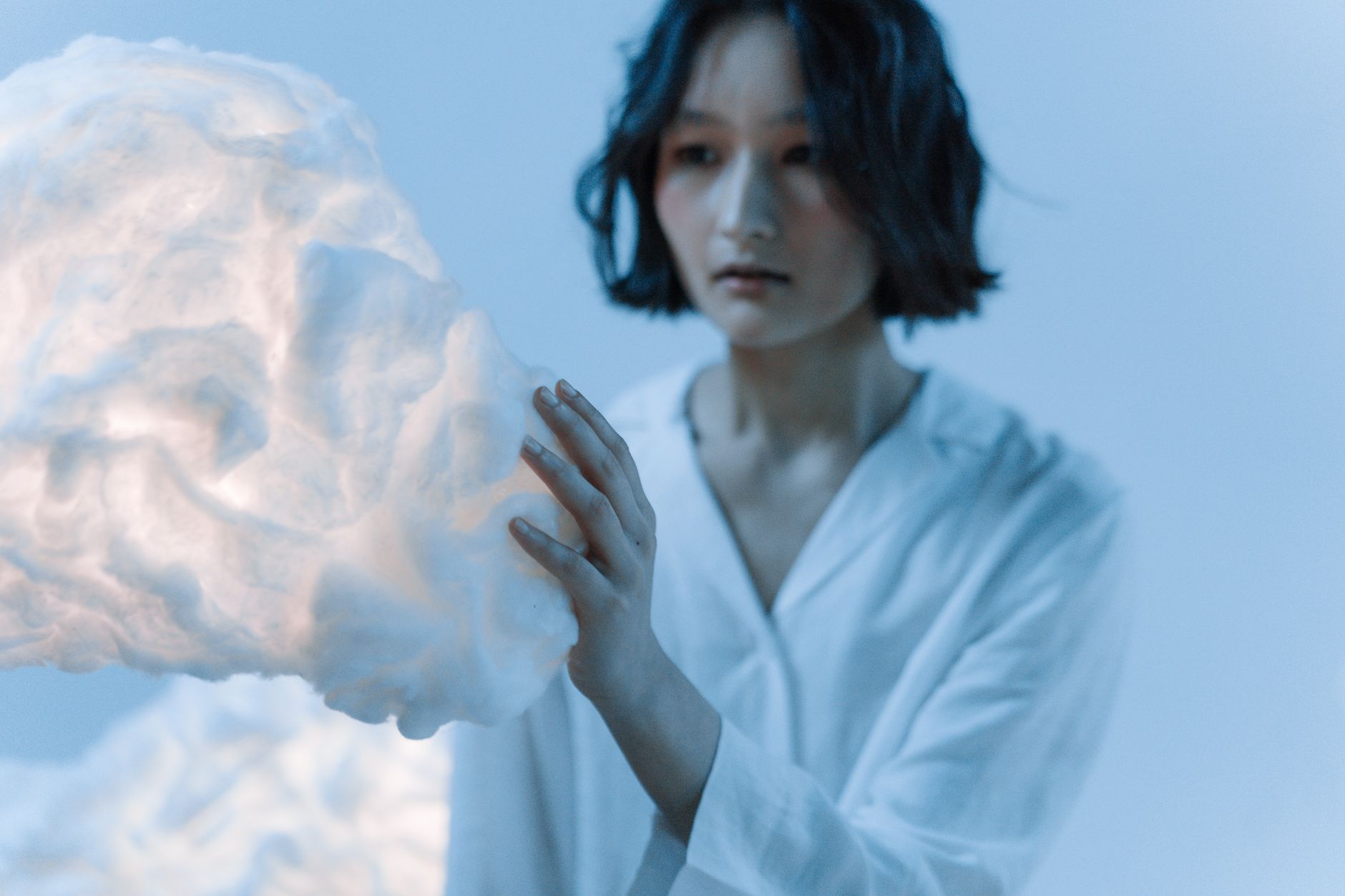 綿雲のオブジェに手を添える女性のバストアップ