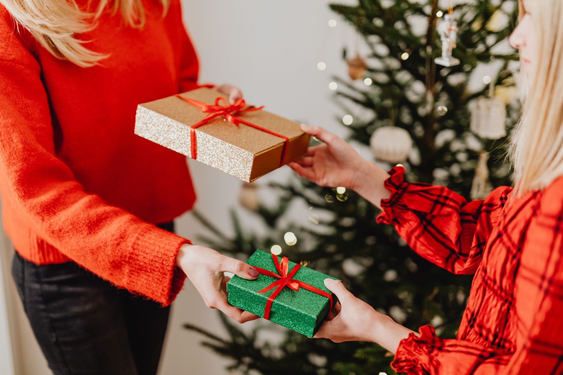 クリスマスツリーの前で赤い箱と緑の箱を交換する二人