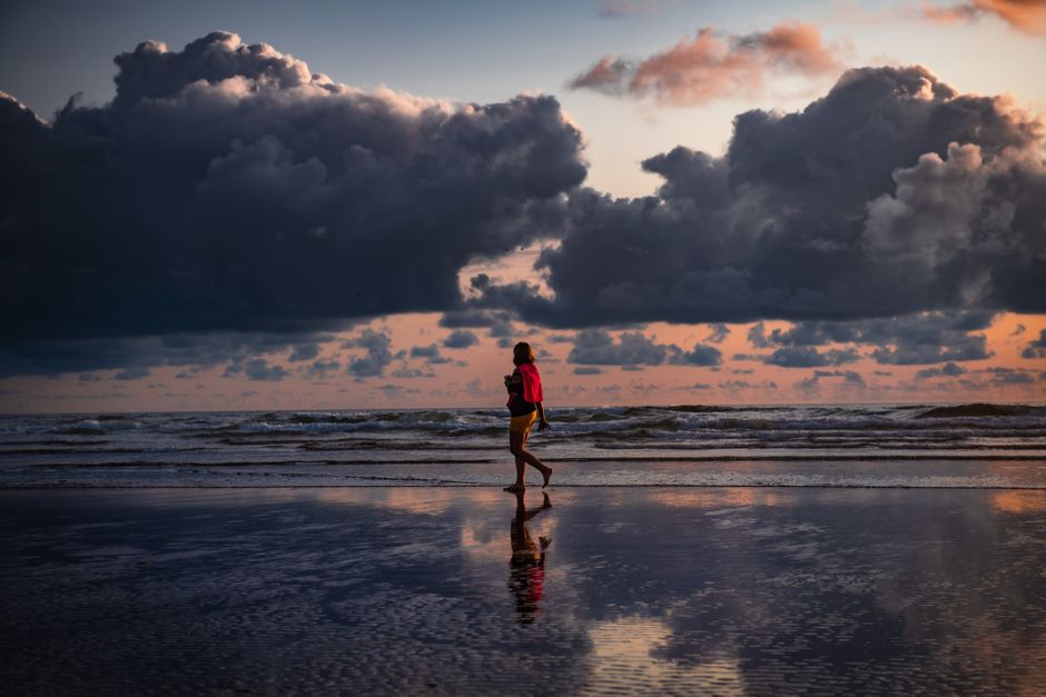 夕暮れの砂浜を歩く女性
