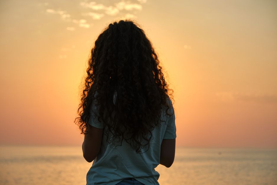夕暮れの海を眺める女性の後ろ姿