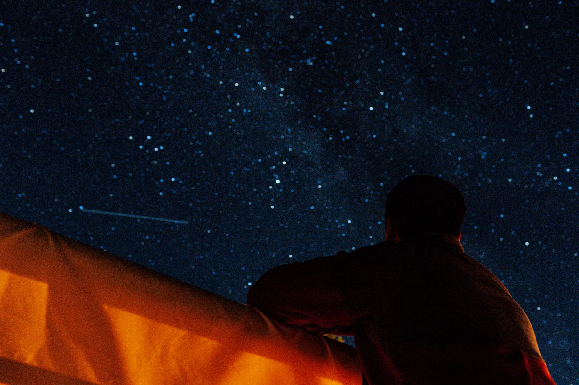 澄んだ星空を見上げて星を眺める人物