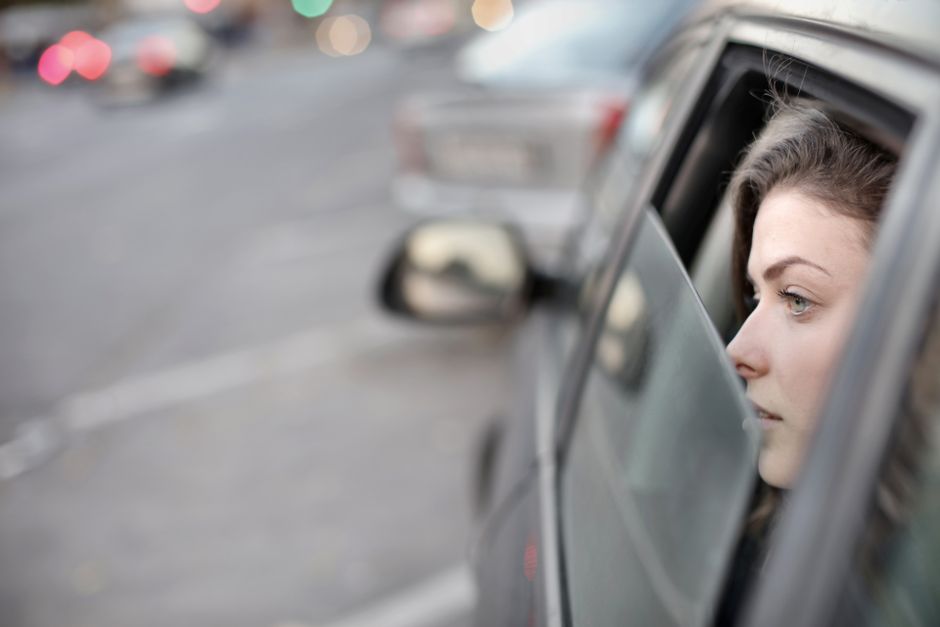 車の窓から街を眺める女性