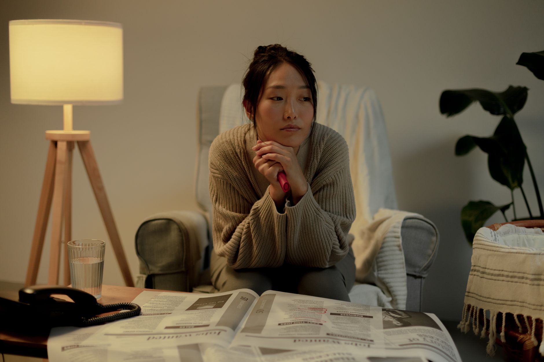 照明のついた薄暗い室内で頬づえをつく女性