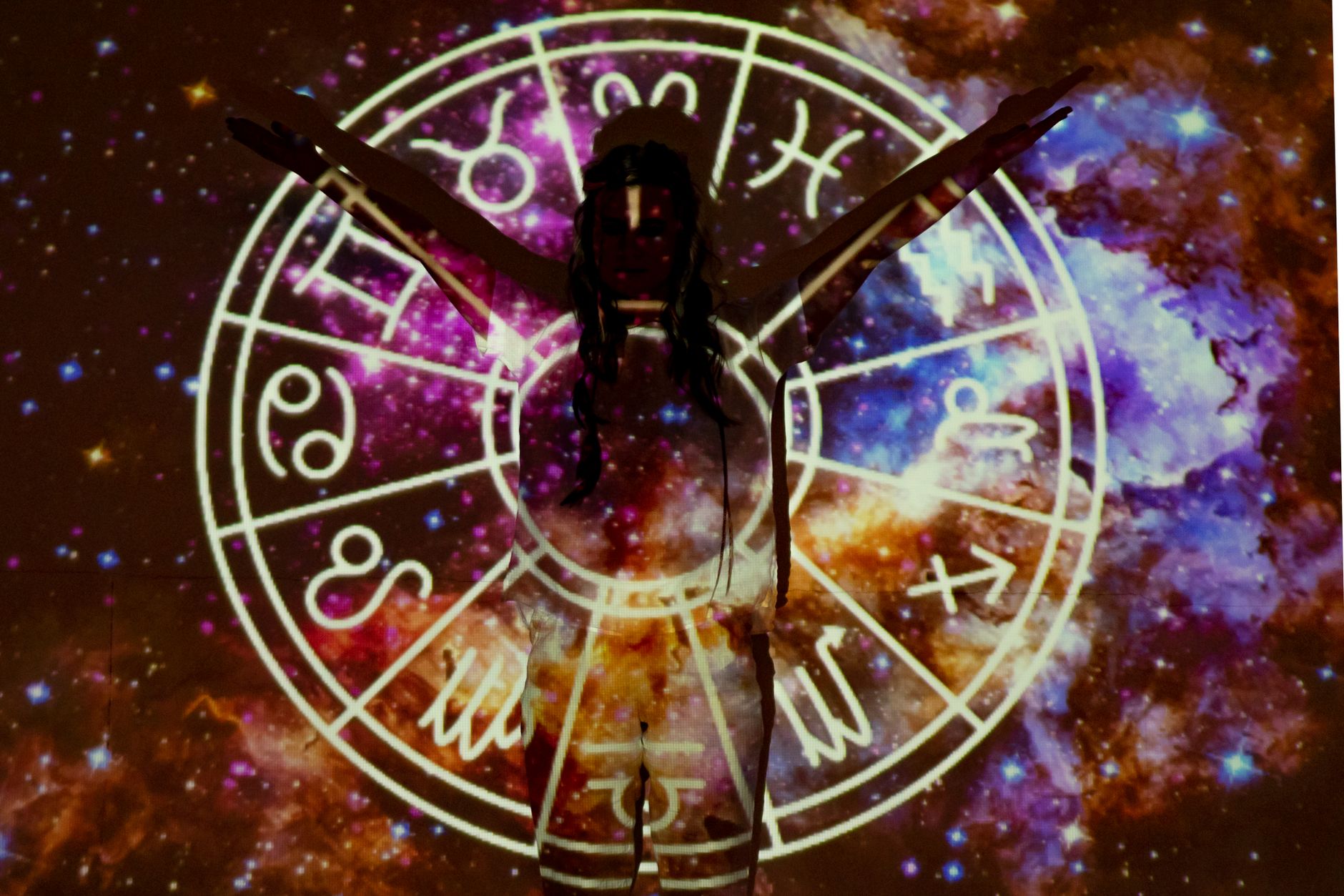 星座のシンボルを背に両手を広げる人物のシルエット