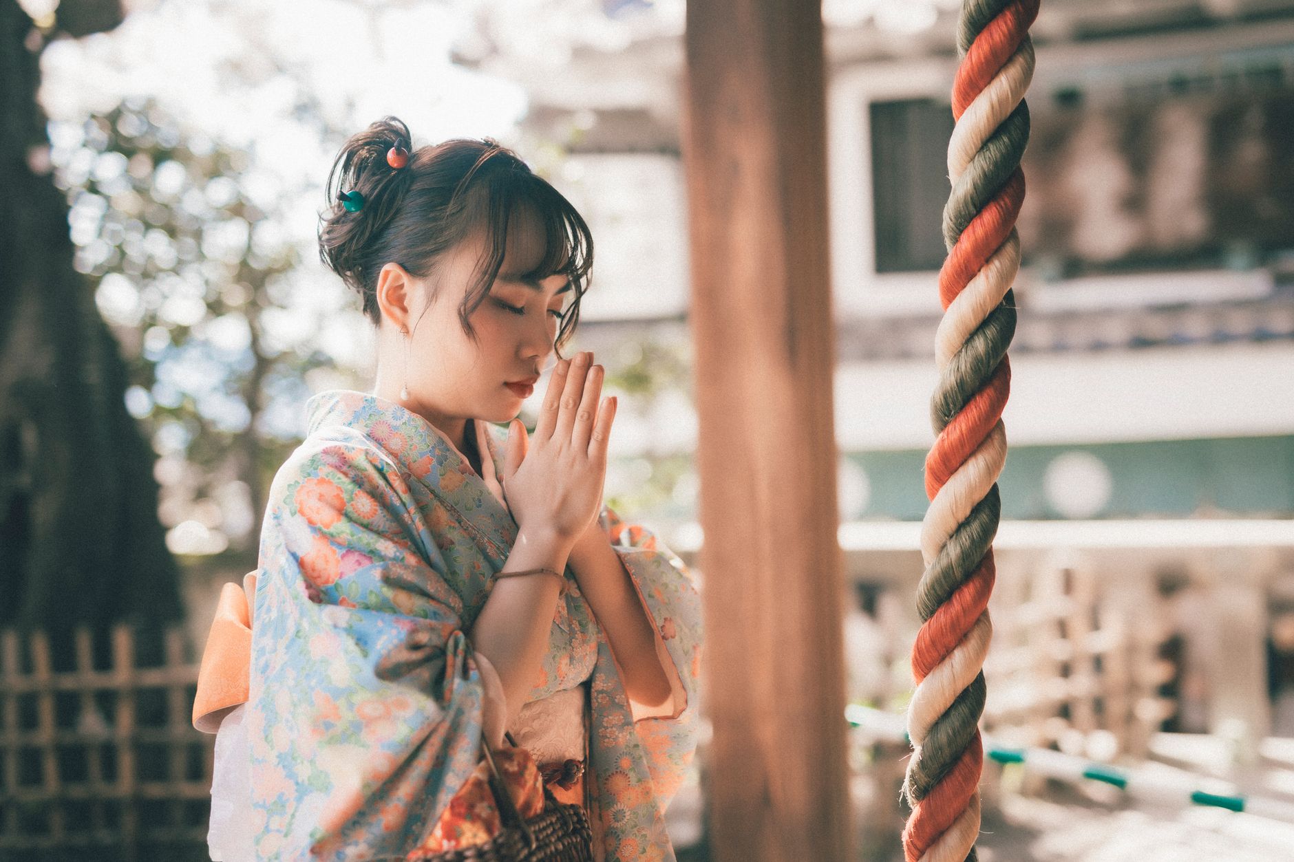 着物姿で拝殿の鈴緒の前に立ち手を合わせる女性