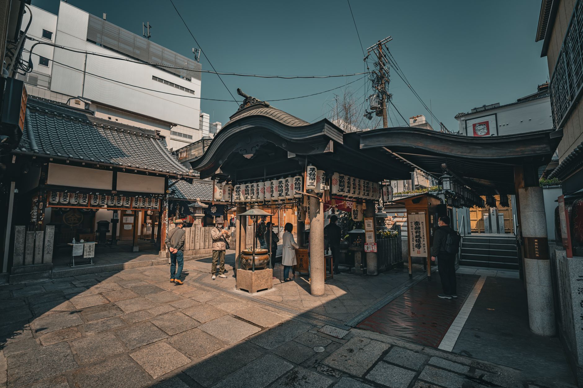 街なかにある寺の境内で香炉の前に立つ参拝者たち