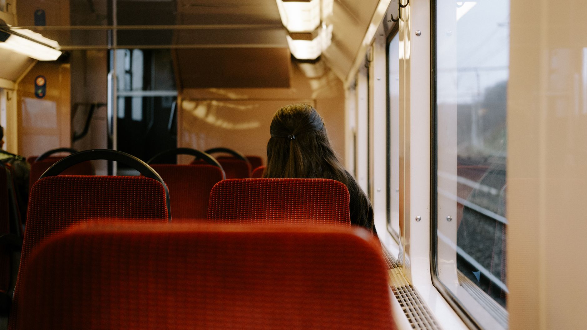 電車の座席で窓の外を眺める女性